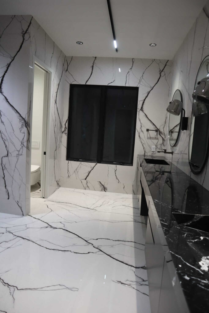 Walk-in shower with marble-look porcelain tile and glass door with black hardware installed by Ceramic Tile Martinez in Indianapolis, Indiana.