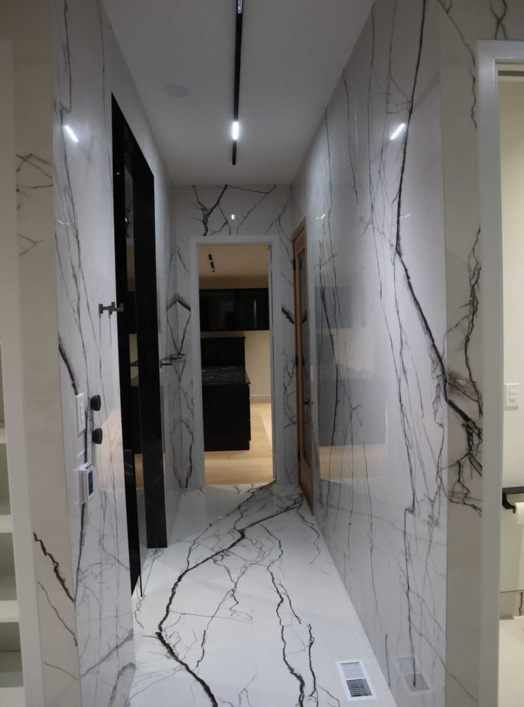 Close-up of marble-look porcelain wall tile with clean cuts around switches and controls by Ceramic Tile Martinez in Fishers, Indiana.